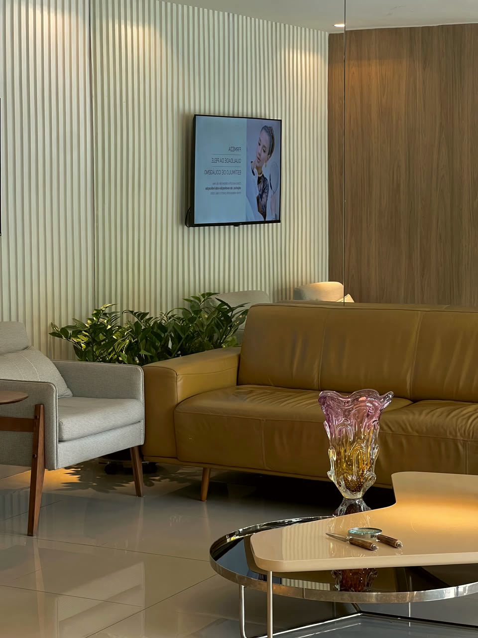 Sala de espera da Clínica Caiena com sofá de couro e painel ripado